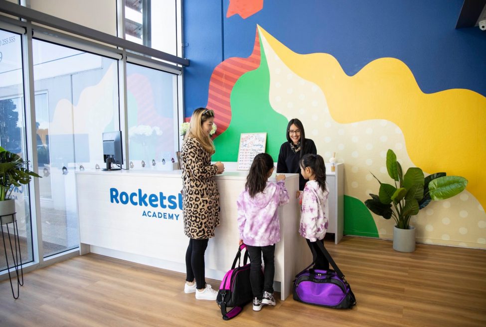 Rocketstars Academy reception counter, with two women and two little kids